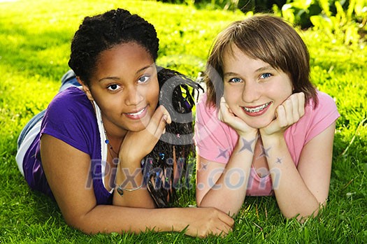Two happy teenage girls laying on grass Two happy teenage girls laying on grass