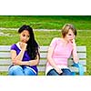 Two bored teenage girls sitting on bench