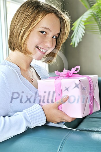 Teenage girl with braces holding wrapped present and smiling Teenage girl with braces holding wrapped present and smiling