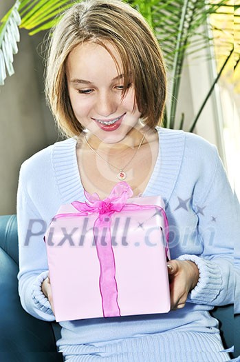 Teenage girl with braces holding wrapped present and smiling Teenage girl with braces holding wrapped present and smiling