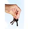 Man's hand holding house keys on blue sky background