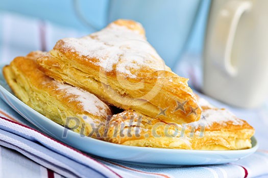 Apple turnovers pastries with coffee cups in the background Apple turnovers pastries with coffee cups in the background