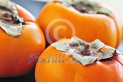 Orange whole ripe persimmon fruit on a plate Orange whole ripe persimmon fruit on a plate