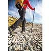 Pretty, young female hiker going uphill, crossing a snow field