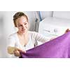 Housework: young woman doing laundry - putting colorful garments into the washing machine (shallow DOF; color toned image)