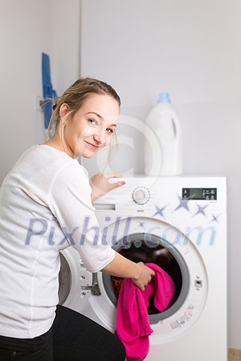 Housework: young woman doing laundry - putting colorful garments into the washing machine (shallow DOF; color toned image) Housework: young woman doing laundry - putting colorful garments into the washing machine (shallow DOF; color toned image)