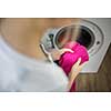 Housework: young woman doing laundry - putting colorful garments into the washing machine (shallow DOF; color toned image)