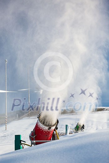 Snow-machine bursting artificial snow over a skiing slope to alow for the skiing season to start Snow-machine bursting artificial snow over a skiing slope to alow for the skiing season to start