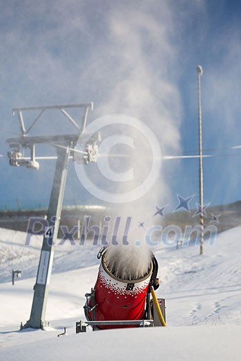 Snow-machine bursting artificial snow over a skiing slope to alow for the skiing season to start Snow-machine bursting artificial snow over a skiing slope to alow for the skiing season to start
