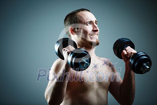 Close up of young man lifting weights over grey background Close up of young man lifting weights over grey background