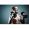 Close up of young man lifting weights over grey background