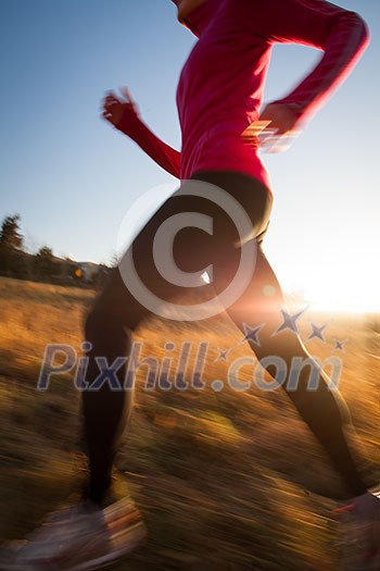 Young woman running outdoors on a lovely sunny winter/fall day (motion blurred image)