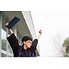 Pretty, young woman celebrating joyfully her graduation - cheking her diploma, happy/impressed with the title she received (color toned image; shallow DOF)