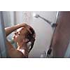 Young woman washing her hair with shampoo, taking a hot long shower