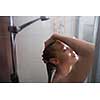 Young woman washing her hair with shampoo, taking a hot long shower