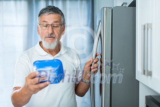 Is this still fine? Senior man in his kitchen by the fridge, looking at the expiry date of a product she took from her fridge - Is this still fine? Senior man in his kitchen by the fridge, looking at the expiry date of a product she took from her fridge -