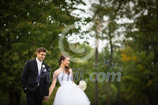 Just married, young wedding couple in a park, walking, savoring the moment on her big day (shallow DOF) Just married, young wedding couple in a park, walking, savoring the moment on her big day (shallow DOF)