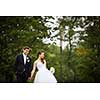 Just married, young wedding couple in a park, walking, savoring the moment on her big day (shallow DOF)