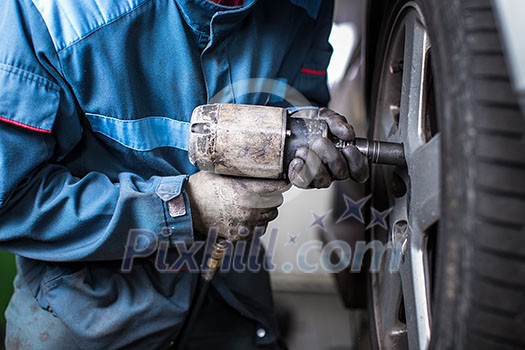 mechanic changing a wheel of a modern car (color toned image) mechanic changing a wheel of a modern car (color toned image)