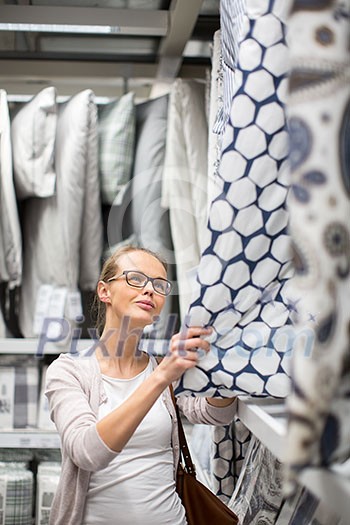 Pretty, young woman choosing the right sheets for her bed in a modern home furnishings store (color toned image; shallow DOF) Pretty, young woman choosing the right sheets for her bed in a modern home furnishings store (color toned image; shallow DOF)