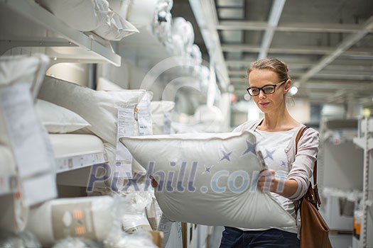 Pretty, young woman choosing the right pillow for her bed in a modern home furnishings store (color toned image; shallow DOF) Pretty, young woman choosing the right pillow for her bed in a modern home furnishings store (color toned image; shallow DOF)
