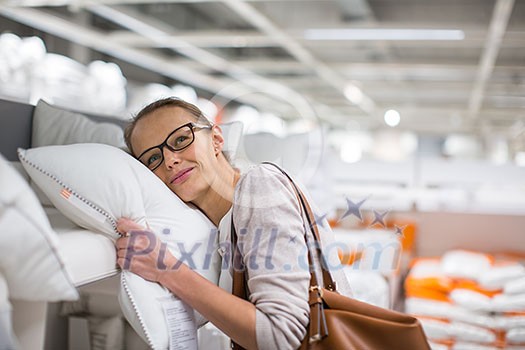 Pretty, young woman choosing the right pillow for her bed in a modern home furnishings store (color toned image; shallow DOF) Pretty, young woman choosing the right pillow for her bed in a modern home furnishings store (color toned image; shallow DOF)