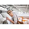 Pretty, young woman choosing the right pillow for her bed in a modern home furnishings store (color toned image; shallow DOF)