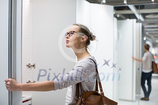 Pretty, young woman choosing the right furniture for her apartment in a modern home furnishings store (color toned image; shallow DOF) Pretty, young woman choosing the right furniture for her apartment in a modern home furnishings store (color toned image; shallow DOF)