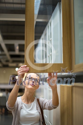 Pretty, young woman choosing the right furniture for her apartment in a modern home furnishings store (color toned image; shallow DOF) Pretty, young woman choosing the right furniture for her apartment in a modern home furnishings store (color toned image; shallow DOF)