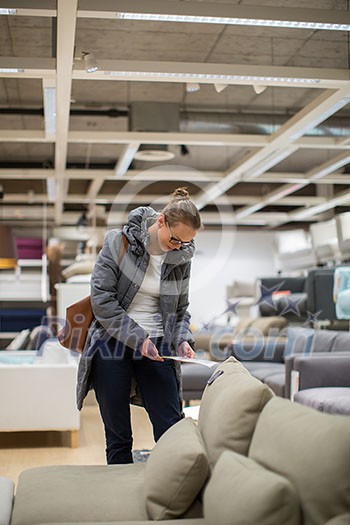 Pretty, young woman choosing the right furniture for her apartment in a modern home furnishings store (color toned image; shallow DOF) Pretty, young woman choosing the right furniture for her apartment in a modern home furnishings store (color toned image; shallow DOF)