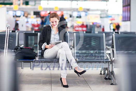 Young female passenger at the airport, using her tablet computer while waiting for her flight (color toned image) Young female passenger at the airport, using her tablet computer while waiting for her flight (color toned image)
