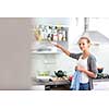 Young woman washing dishes in her modern kitchen, using a dishwasher, putting the dishes in their place