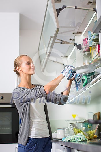 Young woman washing dishes in her modern kitchen, using a dishwasher, putting the dishes in their place Young woman washing dishes in her modern kitchen, using a dishwasher, putting the dishes in their place