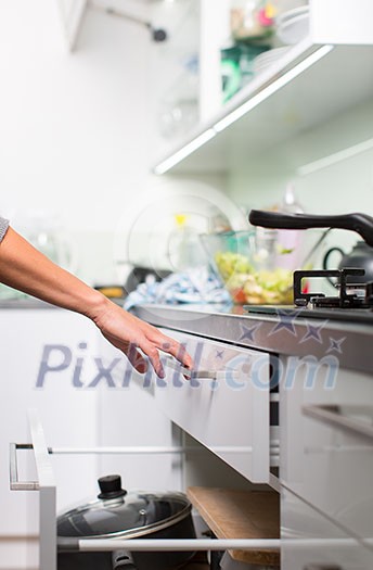 Young woman washing dishes in her modern kitchen, using a dishwasher, putting the dishes in their place Young woman washing dishes in her modern kitchen, using a dishwasher, putting the dishes in their place