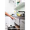 Young woman washing dishes in her modern kitchen, using a dishwasher, putting the dishes in their place