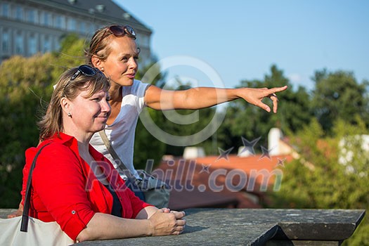 Mother and daughter traveling - two female tourists studying a map, discovering a new city Mother and daughter traveling - two female tourists studying a map, discovering a new city