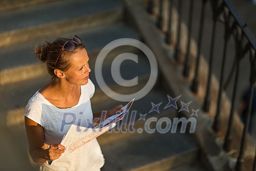 Pretty young female tourist studying a map, enjoying discovering a new city, looking excited (shallow DOF; color toned image) Pretty young female tourist studying a map, enjoying discovering a new city, looking excited (shallow DOF; color toned image)