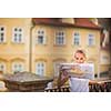 Pretty young female tourist studying a map, enjoying discovering a new city, looking excited (shallow DOF; color toned image)