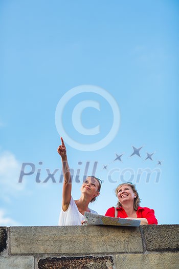 Mother and daughter traveling - two female tourists studying a map, discovering a new city Mother and daughter traveling - two female tourists studying a map, discovering a new city
