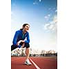 Pretty female runner stretching before her run at a track and field stadium