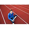 Pretty female runner stretching before her run at a track and field stadium