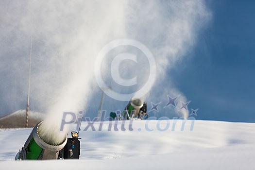 Snow-machine bursting artificial snow over a skiing slope to alow for the skiing season to start Snow-machine bursting artificial snow over a skiing slope to alow for the skiing season to start