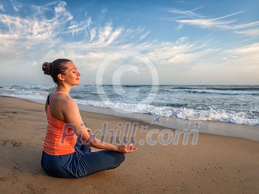 Young sporty fit woman doing yoga - meditating and relaxing in Padmasana Lotus Pose) with chin mudra outdoors at tropical beach on sunset Young sporty fit woman doing yoga - meditating and relaxing in Padmasana Lotus Pose) with chin mudra outdoors at tropical beach on sunset