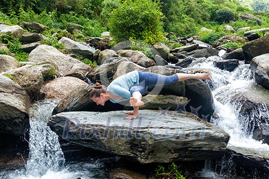 Young sporty fit woman doing yoga asana Eka Pada Koundinyasana 1 at tropical waterfall Young sporty fit woman doing yoga asana Eka Pada Koundinyasana 1 at tropical waterfall