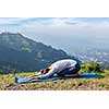 Sporty fit woman practices yoga asana Balasana - child pose outdoors in mountains