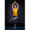 Beautiful sporty fit yogini woman practices yoga asana Vrikshasana - tree pose