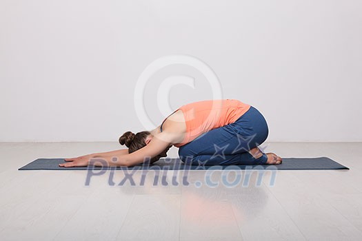 Beautiful sporty fit yogini woman practices yoga asana balasana (child's pose) - resting pose or counter asana for many asanas in studio Beautiful sporty fit yogini woman practices yoga asana balasana (child's pose) - resting pose or counter asana for many asanas in studio