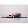 Beautiful sporty fit yogini woman practices yoga asana balasana (child's pose) - resting pose or counter asana for many asanas in studio