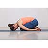 Beautiful sporty fit yogini woman practices yoga asana balasana (child's pose) - resting pose or counter asana for many asanas in studio