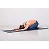 Beautiful sporty fit yogini woman practices yoga asana balasana (child's pose) - resting pose or counter asana for many asanas in studio